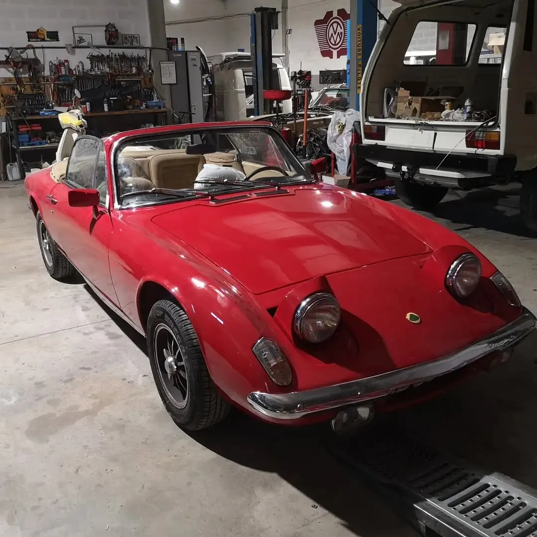 Cabriolet rouge stationné dans l’atelier, devant les outils et un pont élévateur