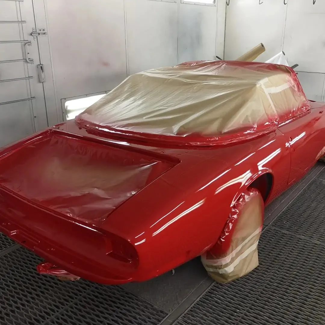 Arrière d’un coupé ancien rouge fraîchement peint et masqué dans une cabine