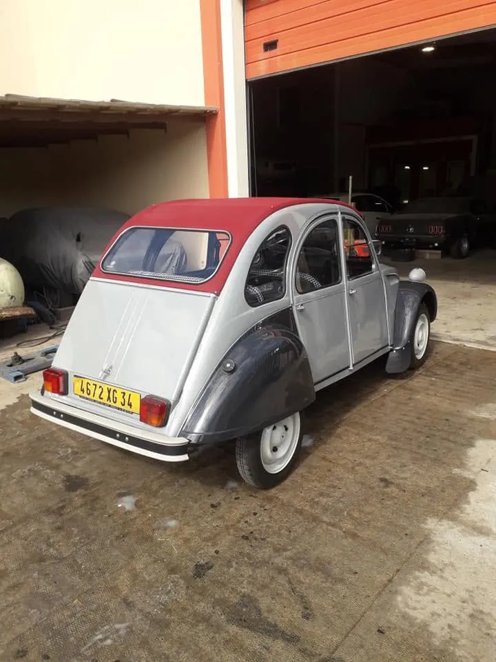 Citroën 2 CV bicolore grise avec capote rouge, vue de trois quarts arrière