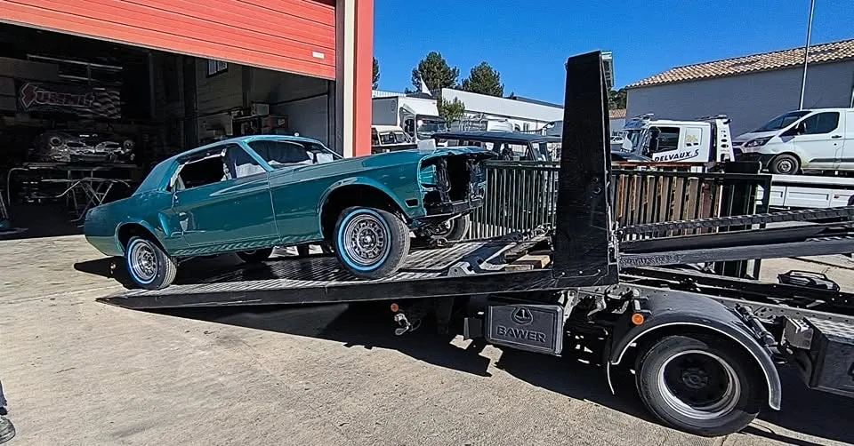 Mustang turquoise partiellement démontée arrivant sur un camion plateau